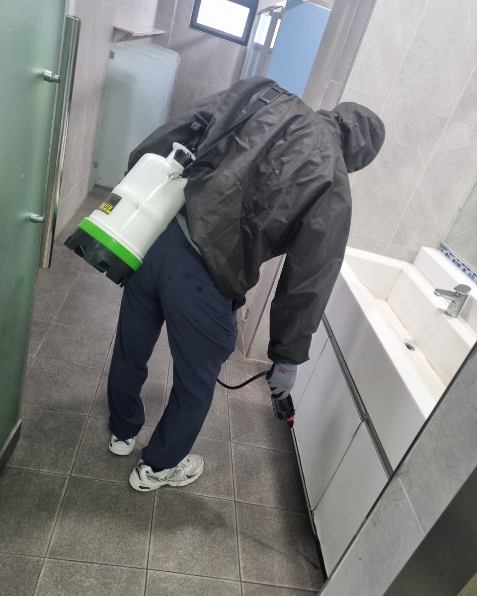 분무기를 메고 화장실을 소독하는 직원