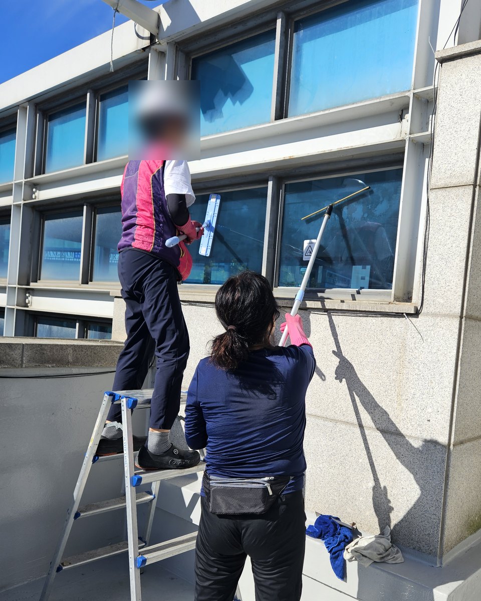 사다리에 올라 건물 바깥 유리창을 닦는 직원들